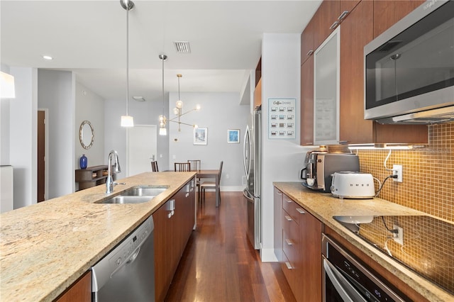 kitchen featuring stainless steel appliances, brown cabinets, a sink, and modern cabinets