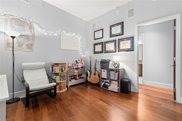 living area featuring visible vents, baseboards, and wood finished floors