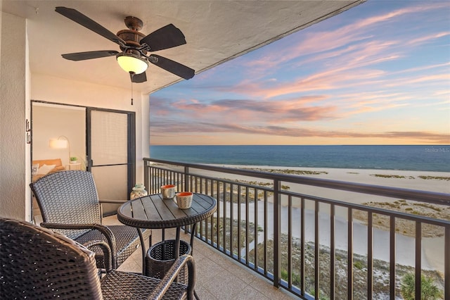 balcony featuring a water view, ceiling fan, and a beach view