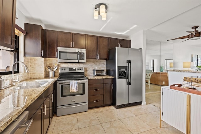 kitchen with light tile patterned floors, dark brown cabinetry, stainless steel appliances, a sink, and tasteful backsplash