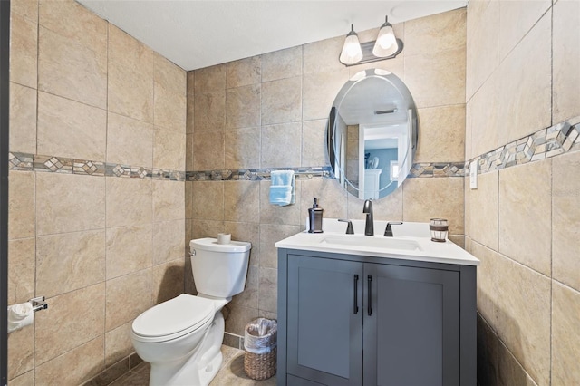 bathroom featuring tile walls, vanity, and toilet