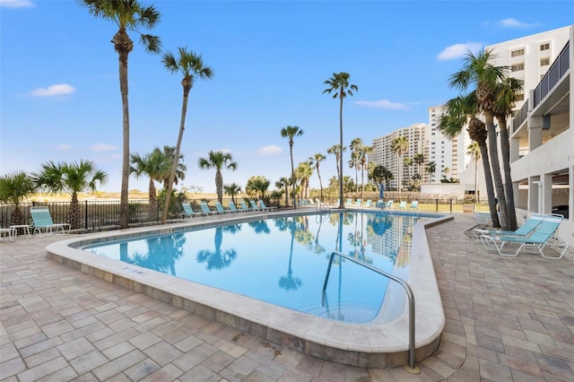 community pool with a patio and fence