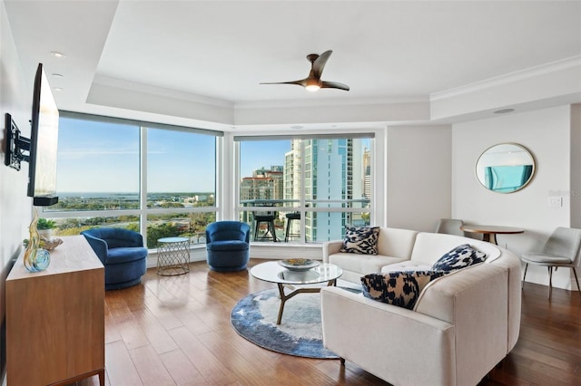 living area with a city view, crown molding, ceiling fan, and wood finished floors