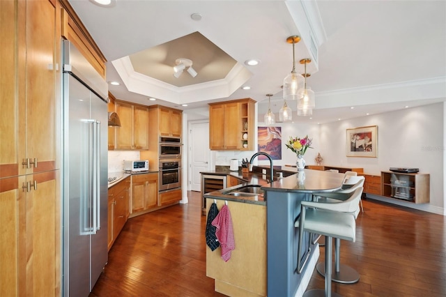 kitchen featuring a sink, open shelves, stainless steel appliances, a breakfast bar area, and a raised ceiling