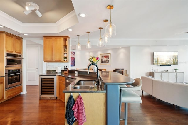 kitchen featuring dark countertops, wine cooler, open floor plan, a breakfast bar area, and a sink