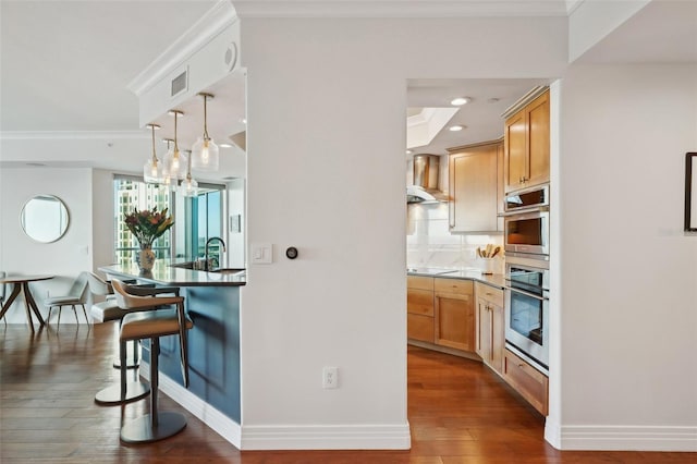 kitchen with visible vents, ornamental molding, backsplash, dark wood finished floors, and wall chimney range hood