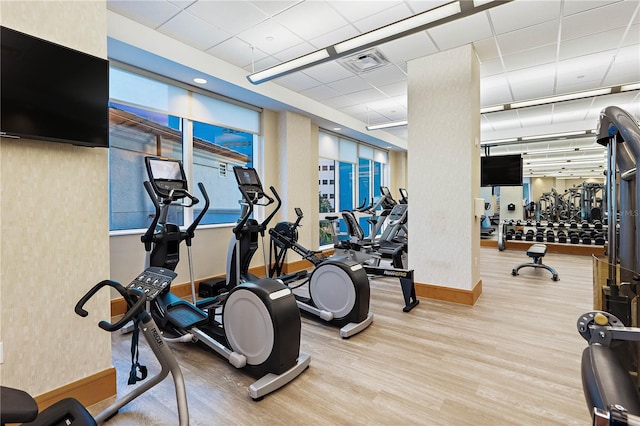 exercise room featuring visible vents, a drop ceiling, baseboards, and wood finished floors