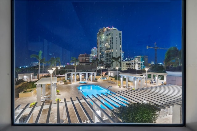 pool at twilight featuring a patio, a view of city lights, a pergola, a gazebo, and a community pool