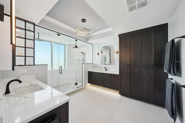 bathroom with a raised ceiling, visible vents, a shower stall, and a sink