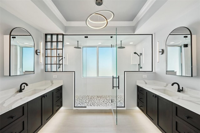 bathroom featuring a raised ceiling, two vanities, a stall shower, and a sink