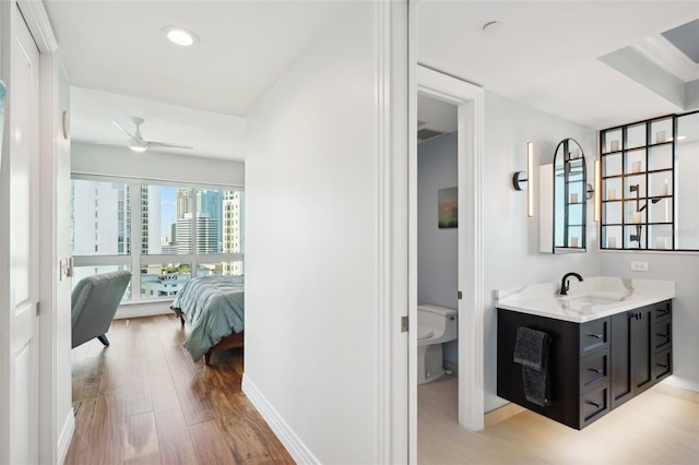 bathroom featuring vanity, wood finished floors, ceiling fan, ensuite bathroom, and toilet