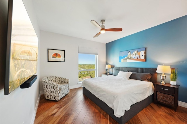 bedroom with a ceiling fan, wood finished floors, and baseboards