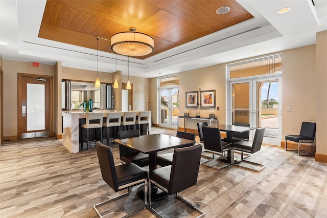 dining area featuring a tray ceiling, wood ceiling, a healthy amount of sunlight, and french doors