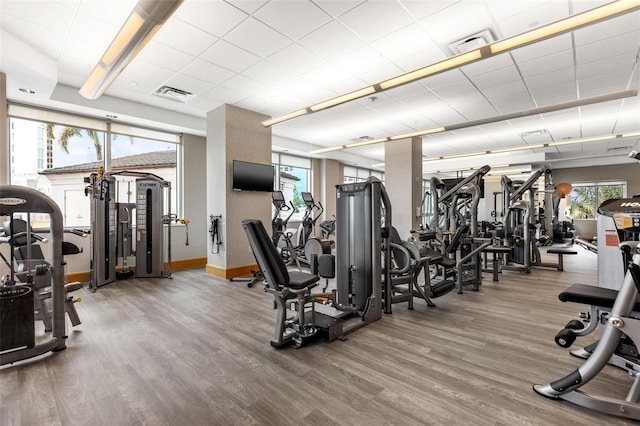 gym with wood finished floors, visible vents, and baseboards