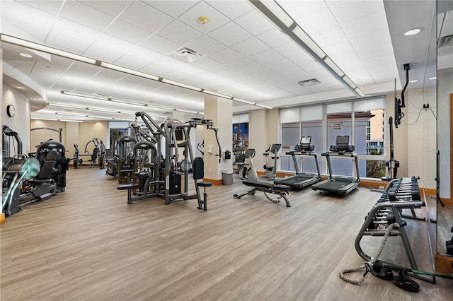 exercise room featuring wood finished floors, visible vents, and baseboards