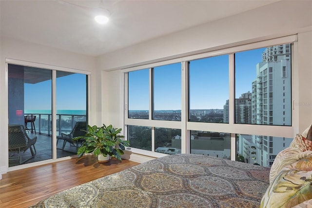 bedroom with access to outside, a view of city, and wood finished floors