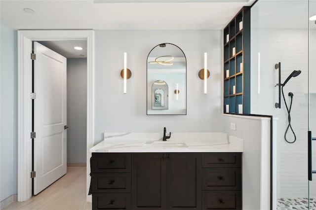 bathroom with tiled shower, vanity, and wood finished floors