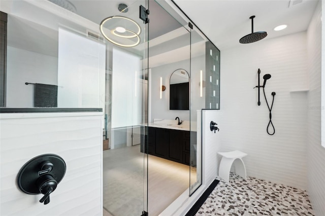 bathroom with a walk in shower, vanity, and visible vents