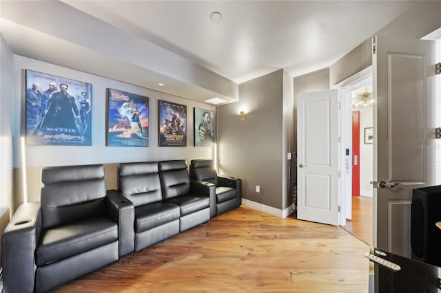 cinema featuring light wood finished floors and baseboards
