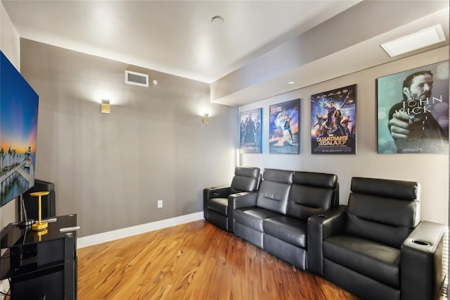 home theater room featuring wood finished floors, baseboards, and visible vents