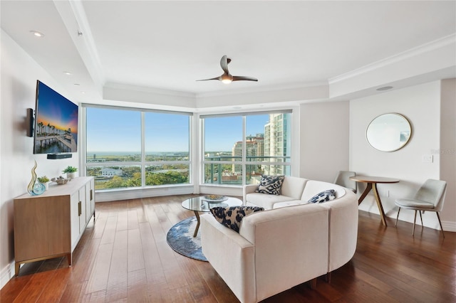 living area featuring a tray ceiling, hardwood / wood-style flooring, crown molding, and ceiling fan