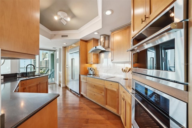 kitchen featuring visible vents, wall chimney exhaust hood, ornamental molding, a tray ceiling, and stainless steel appliances