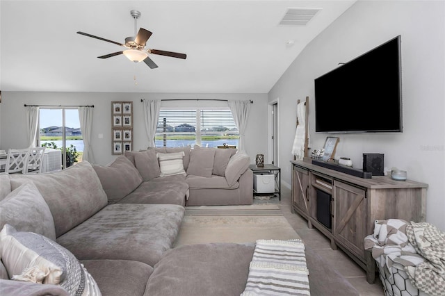 living room with light tile patterned floors, visible vents, a water view, vaulted ceiling, and ceiling fan