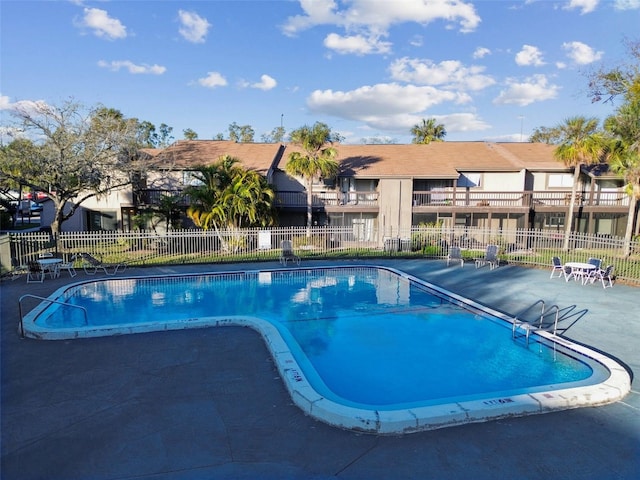 community pool with a residential view, fence, and a patio