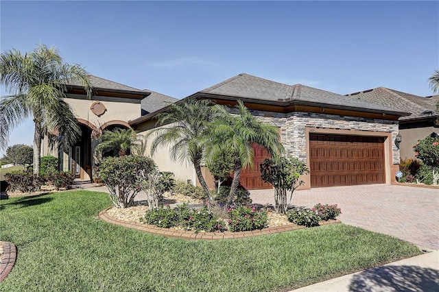 view of front of house with a garage, stone siding, decorative driveway, a front yard, and stucco siding