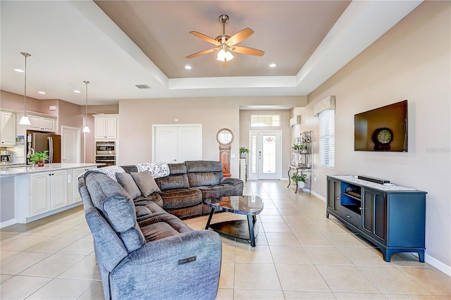 living room featuring light tile patterned floors, baseboards, and a raised ceiling