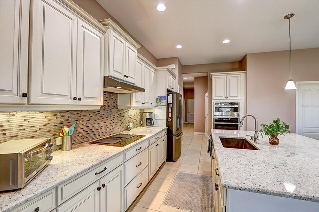 kitchen with a center island with sink, stainless steel appliances, under cabinet range hood, a sink, and light tile patterned flooring