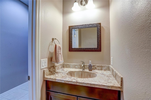 bathroom with tile patterned floors, a textured wall, and vanity