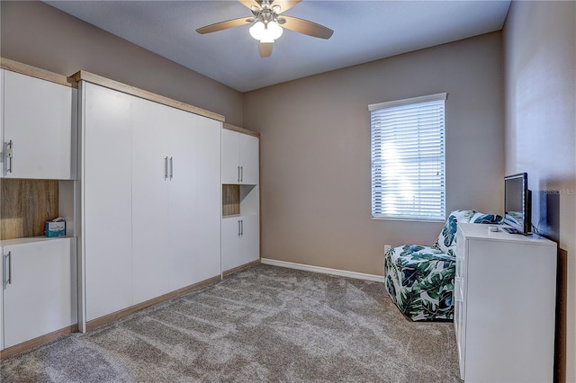 interior space featuring baseboards, a ceiling fan, and light colored carpet