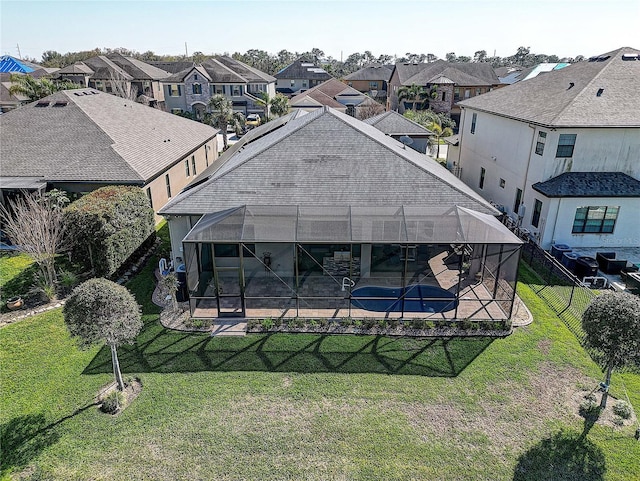 rear view of house with a patio, glass enclosure, a lawn, and a residential view
