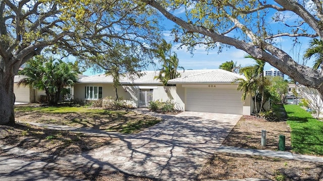 single story home with driveway, an attached garage, a tiled roof, and stucco siding