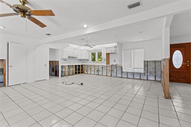 unfurnished living room with visible vents, ceiling fan, and light tile patterned floors