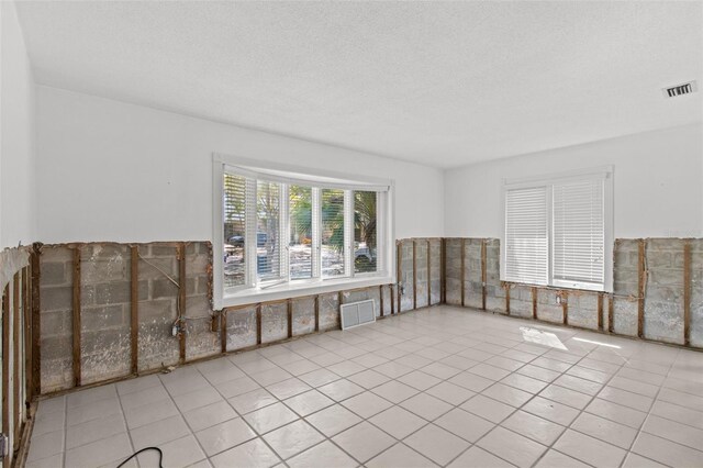 empty room with a textured ceiling, visible vents, and tile patterned floors