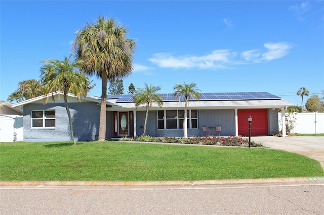 ranch-style home with concrete driveway, an attached garage, fence, and roof mounted solar panels