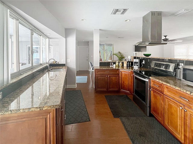 kitchen featuring island range hood, stainless steel appliances, a sink, visible vents, and brown cabinets