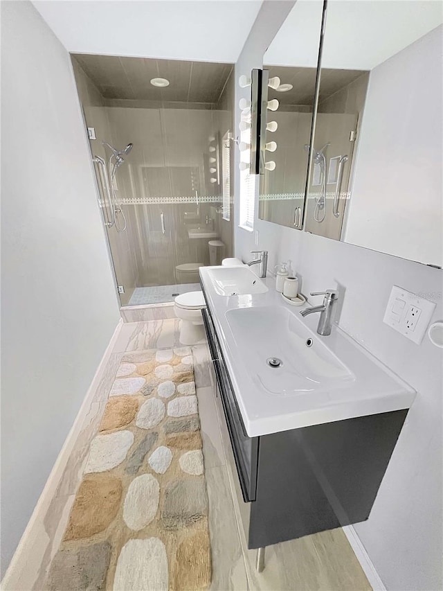 bathroom featuring a sink, a shower stall, toilet, and double vanity