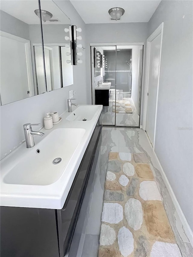 bathroom with double vanity, baseboards, and a sink