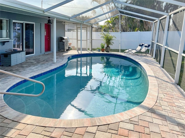 view of swimming pool with a patio, glass enclosure, a fenced backyard, grilling area, and a fenced in pool