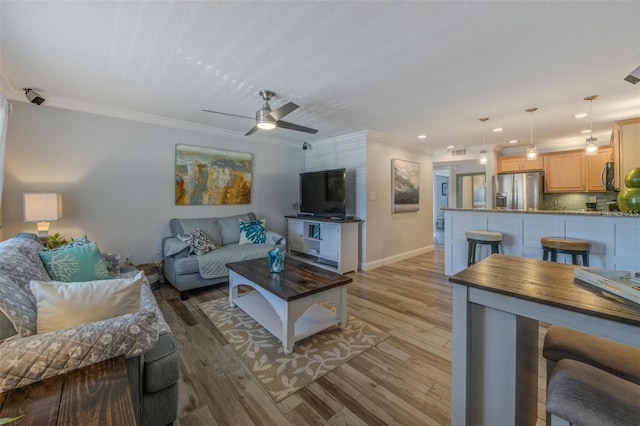 living area featuring baseboards, visible vents, a ceiling fan, light wood-style flooring, and ornamental molding