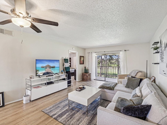 living area featuring visible vents, a ceiling fan, a textured ceiling, light wood-type flooring, and baseboards