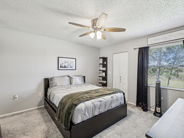 bedroom with baseboards, light colored carpet, ceiling fan, a textured ceiling, and a closet