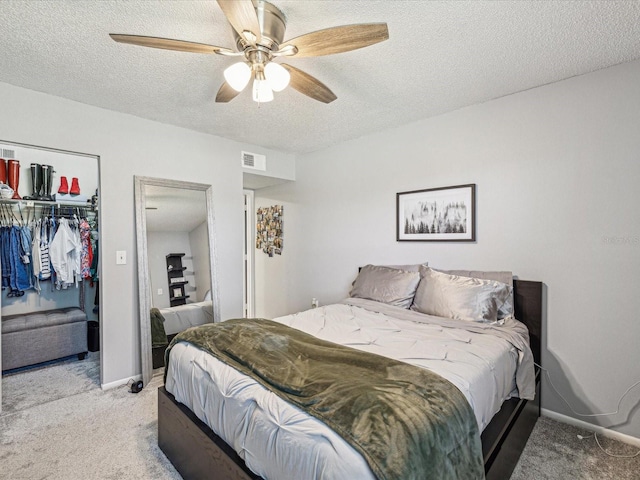 bedroom with a textured ceiling, light carpet, visible vents, baseboards, and a closet