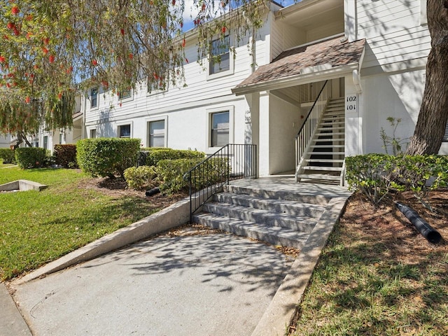 entrance to property with a yard and stucco siding