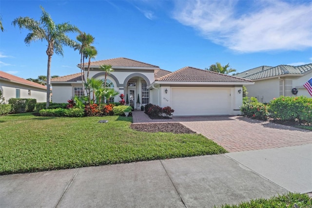 view of front of house with a tile roof, an attached garage, decorative driveway, a front lawn, and stucco siding