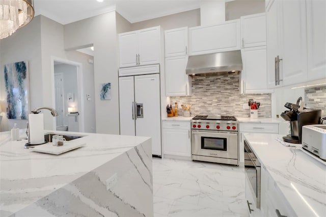 kitchen featuring white cabinets, wall chimney exhaust hood, built in appliances, marble finish floor, and backsplash