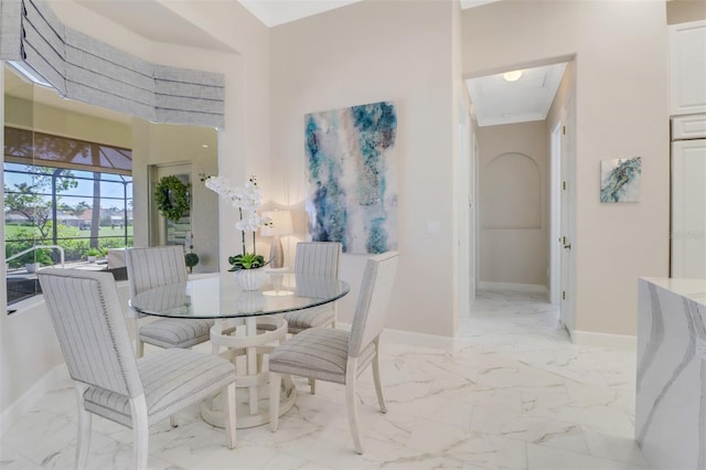 dining space with marble finish floor, a towering ceiling, and baseboards